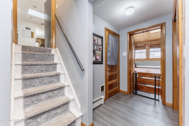 entryway with a baseboard heating unit, baseboards, visible vents, wood finished floors, and stairs