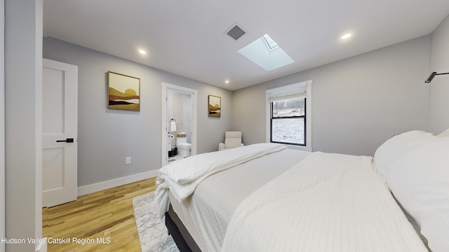 bedroom featuring light hardwood / wood-style floors, connected bathroom, and a skylight