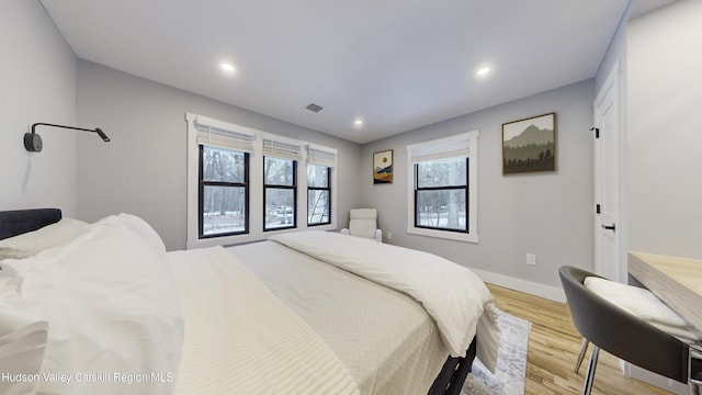 bedroom with multiple windows and light hardwood / wood-style flooring