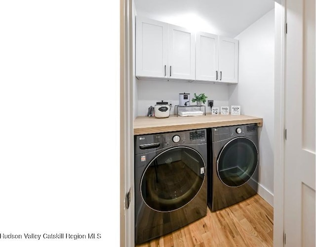 laundry area featuring cabinets, washer and clothes dryer, and light wood-type flooring