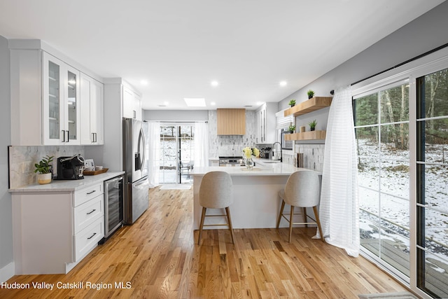 kitchen featuring decorative backsplash, white cabinetry, stainless steel fridge, and wine cooler