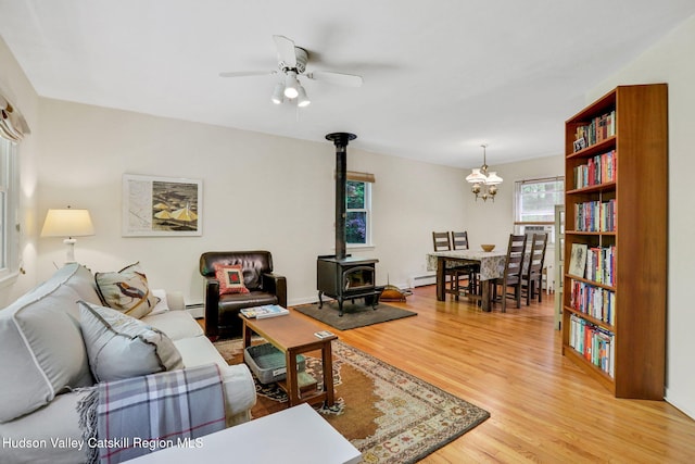 512 Watson Woods Rd, Lake Hill, NY 12448 - living room with a wood stove, light wood finished floors, a ceiling fan, a chandelier, and a baseboard radiator