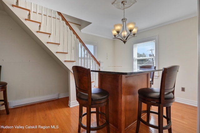 bar featuring a notable chandelier, a healthy amount of sunlight, light wood-style floors, and baseboard heating
