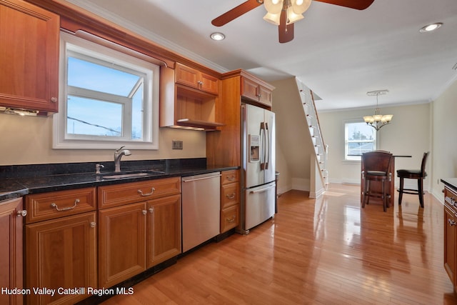kitchen featuring light wood-type flooring, stainless steel appliances, ceiling fan with notable chandelier, a sink, and brown cabinetry