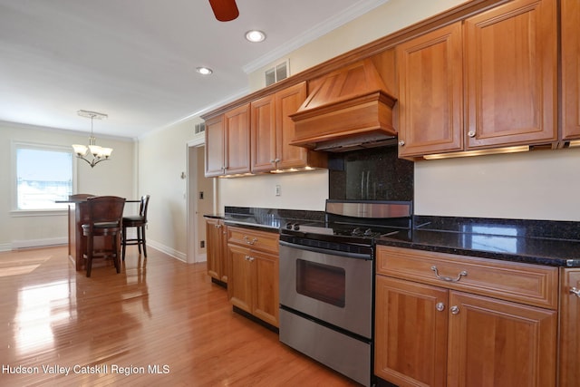 kitchen with visible vents, custom exhaust hood, crown molding, brown cabinets, and stainless steel range oven