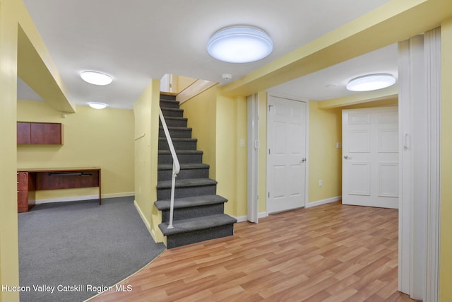 finished basement with baseboards, stairs, and wood finished floors