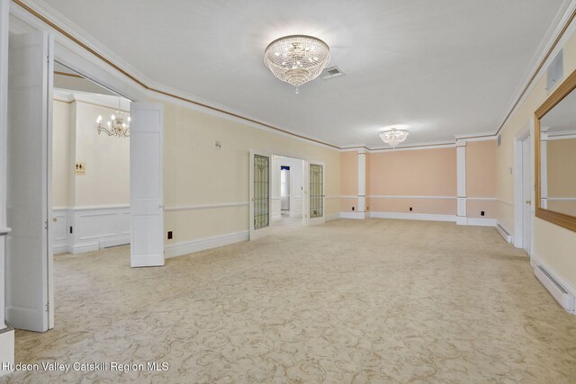 carpeted empty room with a baseboard radiator, crown molding, a decorative wall, and an inviting chandelier