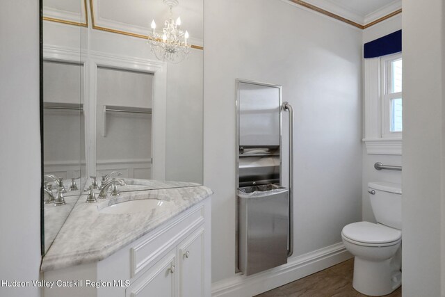 bathroom featuring vanity, crown molding, toilet, baseboards, and a notable chandelier