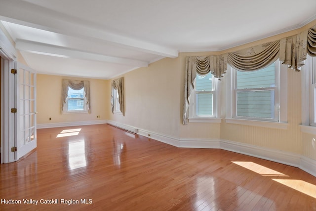 spare room featuring baseboards, beam ceiling, and hardwood / wood-style flooring