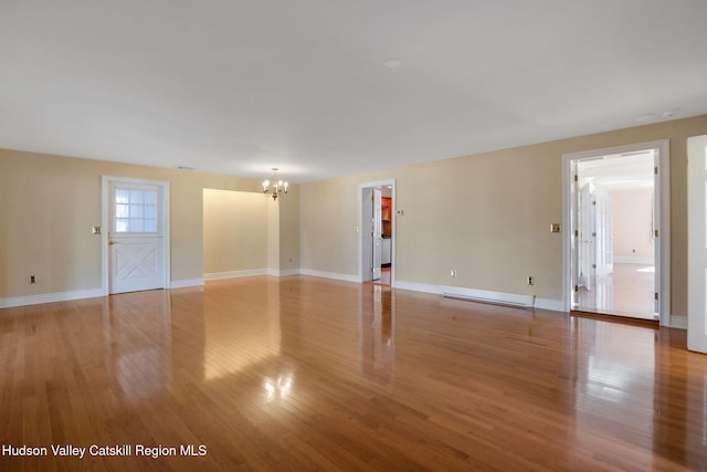 empty room featuring baseboards, a chandelier, and light wood-style floors