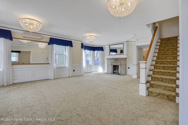 unfurnished living room featuring carpet floors, stairway, a decorative wall, an AC wall unit, and an inviting chandelier