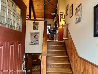 212 S St, Windham, NY 12496 - stairs with wooden ceiling, wooden walls, a wainscoted wall, a ceiling fan, and a towering ceiling