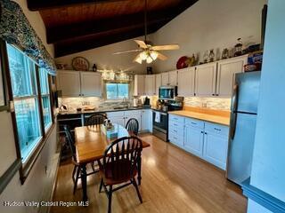 212 S St, Windham, NY 12496 - kitchen featuring stainless steel appliances, tasteful backsplash, white cabinets, and light wood-style flooring