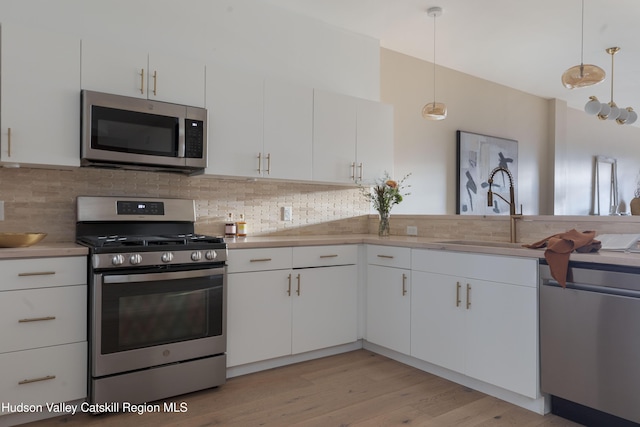 kitchen with decorative light fixtures, tasteful backsplash, sink, stainless steel appliances, and white cabinets