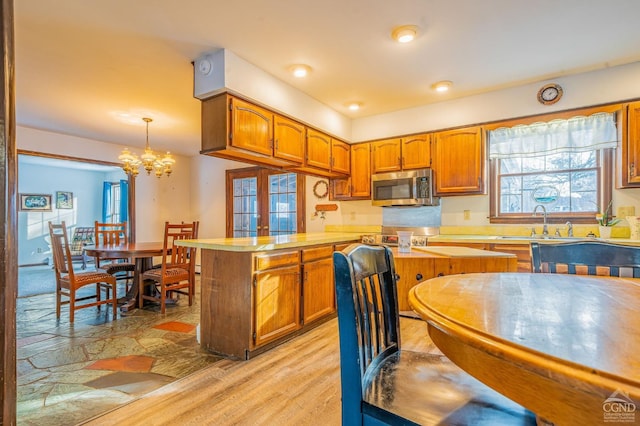 176 High Rock Rd, West Coxsackie, NY 12192 - kitchen with stainless steel microwave, brown cabinetry, a peninsula, and a chandelier