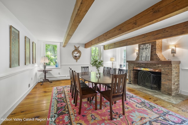 202 Buckwheat Bridge Rd, Germantown, NY 12526 - dining space with wood-type flooring, a brick fireplace, baseboard heating, baseboards, and beamed ceiling