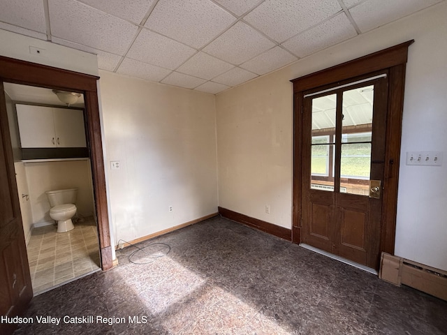 interior space with a paneled ceiling and a baseboard heating unit