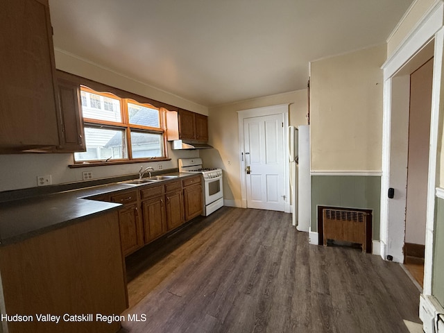 kitchen featuring white appliances, dark wood-type flooring, radiator, a baseboard heating unit, and sink