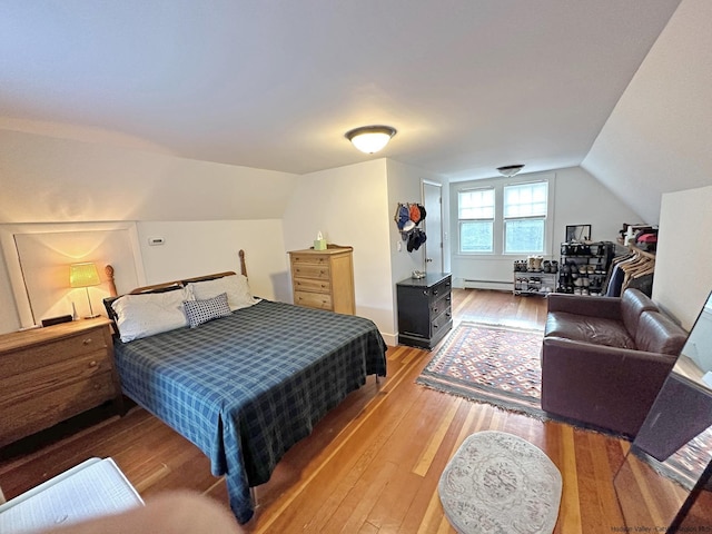 bedroom featuring vaulted ceiling, a baseboard heating unit, and hardwood / wood-style floors