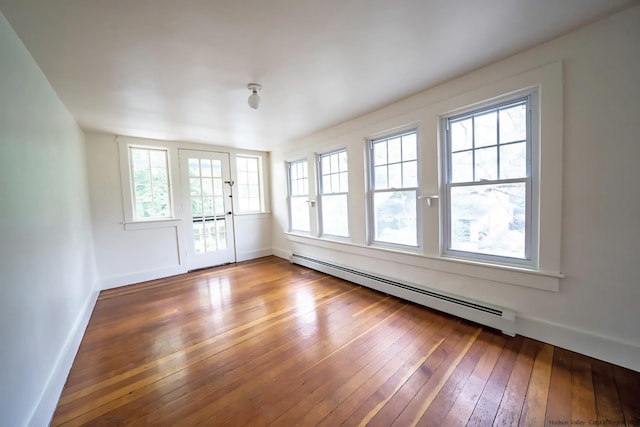 unfurnished room with a baseboard heating unit and hardwood / wood-style floors