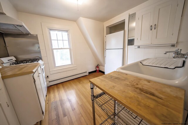 kitchen with baseboard heating, white cabinets, exhaust hood, white fridge, and light hardwood / wood-style floors