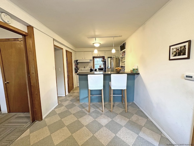 kitchen featuring decorative light fixtures, kitchen peninsula, a kitchen breakfast bar, white cabinets, and stainless steel fridge