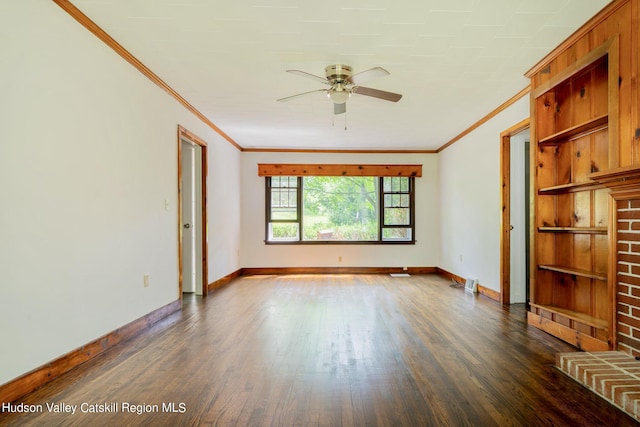 spare room with a brick fireplace, ceiling fan, dark wood-type flooring, and ornamental molding