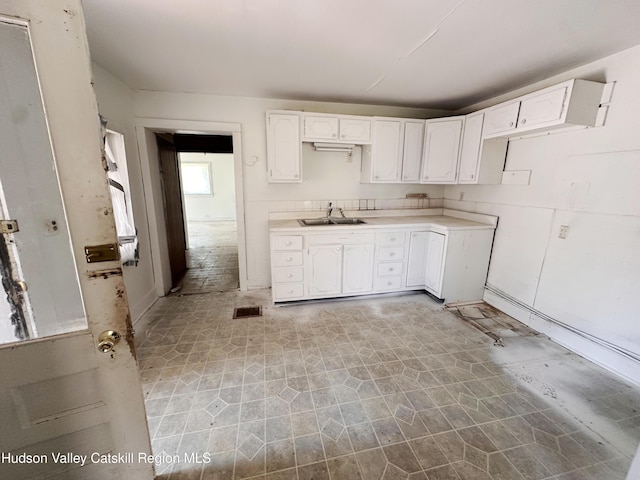 kitchen with visible vents, a sink, white cabinetry, and light countertops