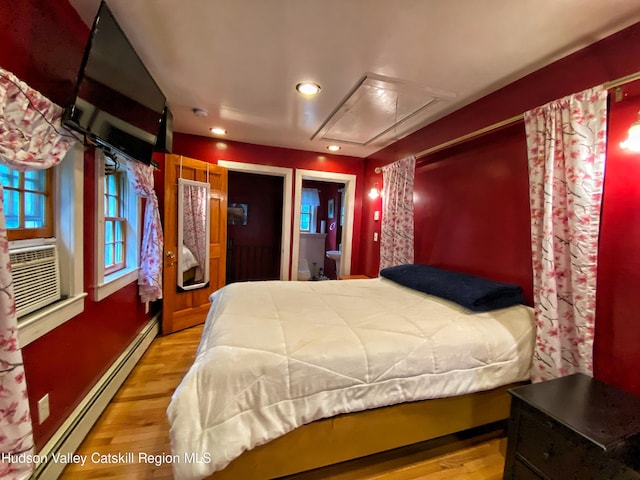 bedroom featuring light hardwood / wood-style flooring, cooling unit, and a baseboard heating unit