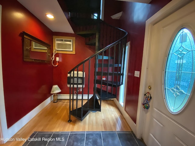 entryway featuring hardwood / wood-style flooring, an AC wall unit, and baseboard heating