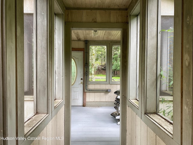 doorway to outside with wood walls, hardwood / wood-style floors, and wood ceiling