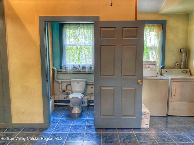 bathroom with tile patterned flooring, washer and dryer, and toilet