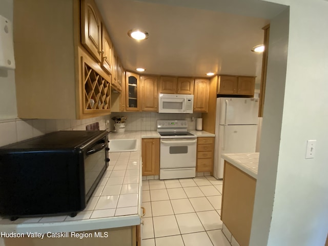 kitchen with tile counters, light tile patterned flooring, white appliances, and tasteful backsplash