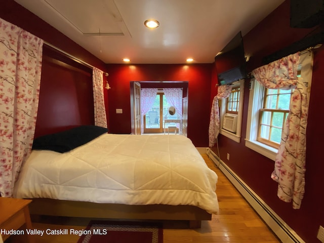 bedroom with a baseboard radiator, hardwood / wood-style flooring, and cooling unit