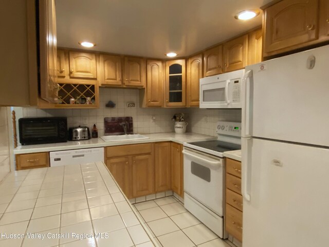 kitchen with white appliances, sink, light tile patterned floors, and tasteful backsplash