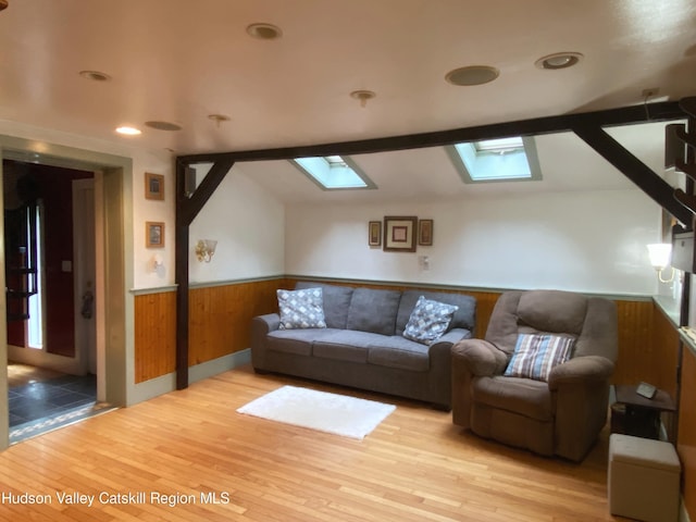 living room featuring light hardwood / wood-style floors and vaulted ceiling with skylight