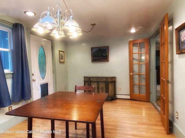 dining area featuring light hardwood / wood-style flooring, a chandelier, french doors, and a baseboard heating unit