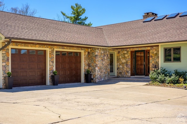 234 Botti Dr, Hunter, NY 12442 - property entrance featuring stone siding, roof with shingles, concrete driveway, an attached garage, and a chimney