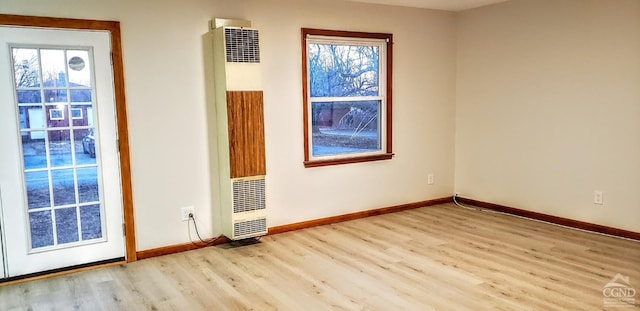 spare room with a heating unit, wood finished floors, and baseboards