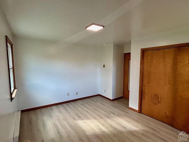 unfurnished bedroom with light wood finished floors, a closet, and baseboards