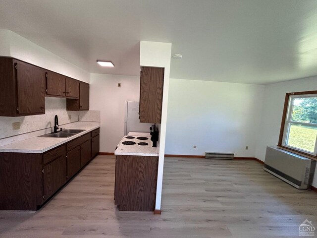 kitchen with a sink, radiator heating unit, light countertops, and dark brown cabinets