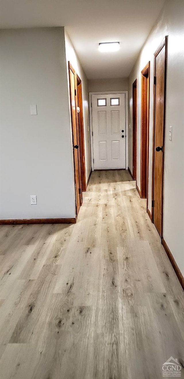 hall with light wood-style flooring and baseboards