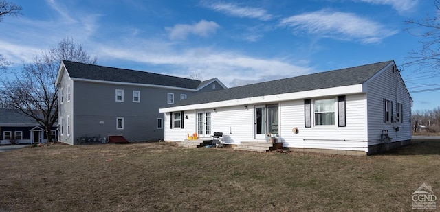 back of property with a lawn and a shingled roof