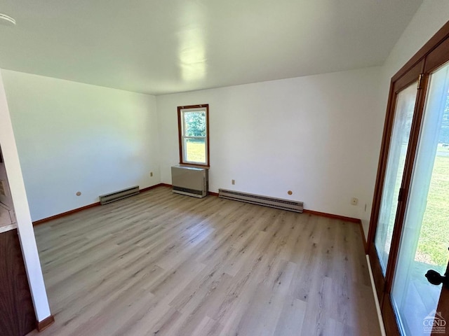 unfurnished room with a baseboard heating unit, light wood-type flooring, and baseboards