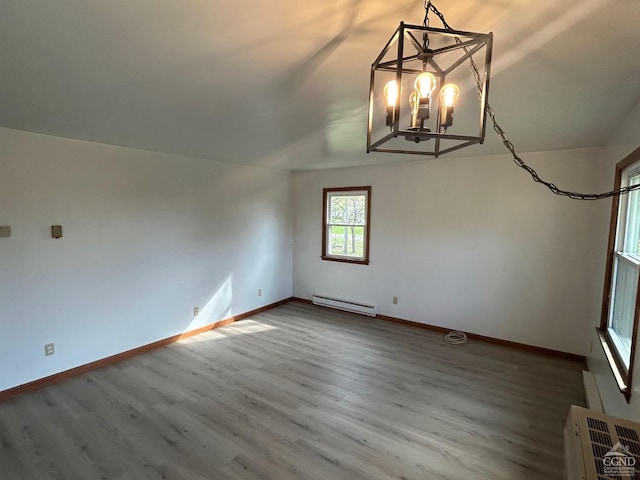 unfurnished dining area with baseboard heating, a chandelier, wood finished floors, and baseboards