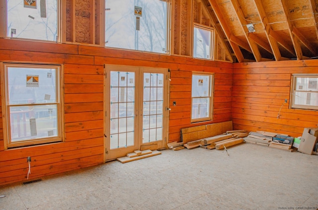 unfurnished living room with a wealth of natural light, lofted ceiling, and wood walls