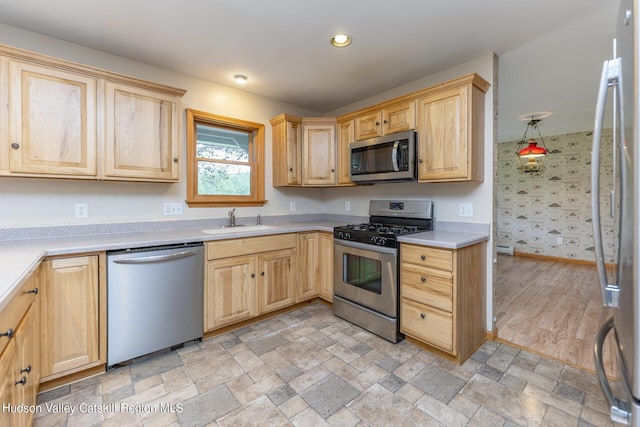 kitchen with light brown cabinetry, sink, pendant lighting, and appliances with stainless steel finishes