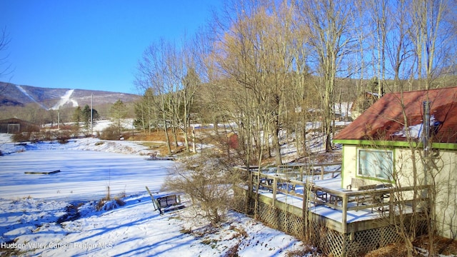 yard layered in snow with a deck with mountain view