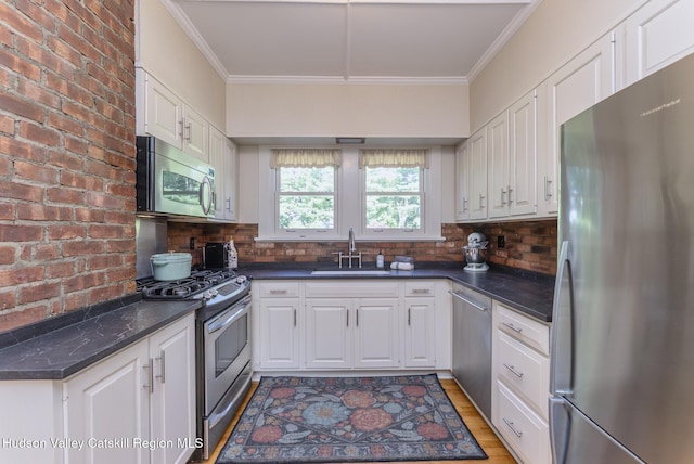280 Pitcher Ln, Red Hook, NY 12571 - kitchen with appliances with stainless steel finishes, dark countertops, ornamental molding, white cabinetry, and backsplash