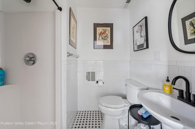 bathroom featuring walk in shower, toilet, sink, heating unit, and tile walls